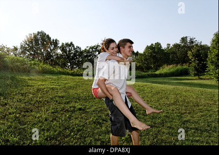 Junger Mann junge Frau Huckepack Fahrt geben Stockfoto