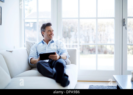 Mann auf Sofa mit digital-Tablette Stockfoto