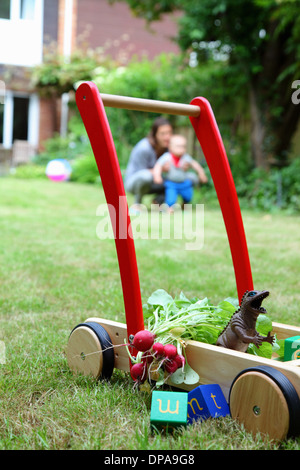 Mutter und Kind mit Push Cart und Spielzeug im Garten Stockfoto