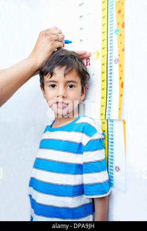 Junge stand gegen Höhe Diagramm gemessen wird Stockfoto