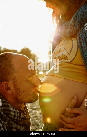 Schwangere Frau mit Partner küssen Beule Stockfoto