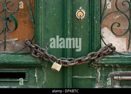 Detail einer alten, grünen Tür mit Vorhängeschloss angekettet Stockfoto