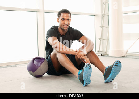 Mann sitzt auf dem Boden im gymnasium Stockfoto