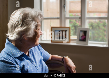 Ältere Erwachsene Frau im Zimmer Blick aus Fenster Stockfoto