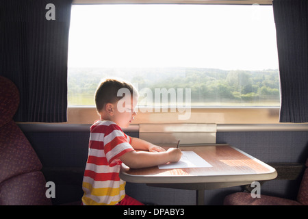 Kleiner Junge mit Bleistift und Papier auf Zug Stockfoto