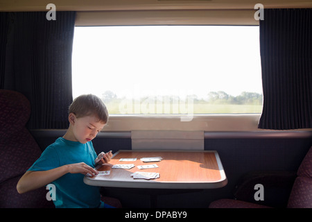 Junge mit Spielkarten auf Zug Stockfoto