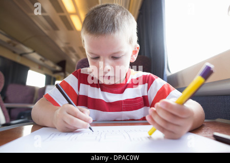 Junge mit Bleistift, Feder und Papier auf Zug Stockfoto