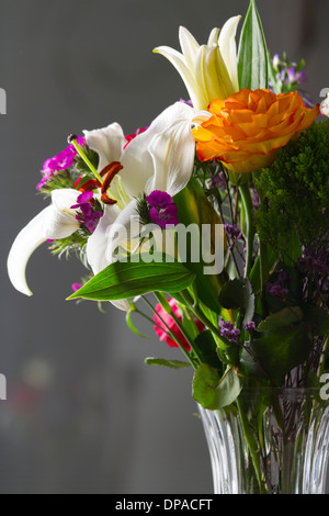 Bunte Blumen-Arrangement von Lilien und Rosen in einer Vase klar Stockfoto