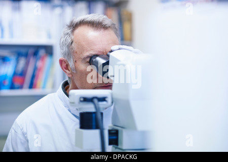 Mann auf der Suche durch Mikroskop Stockfoto
