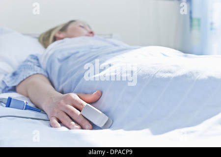 Patienten am Krankenbett mit Monitor am Finger liegen Stockfoto