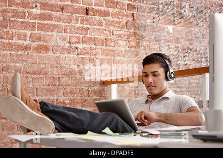 Junger Mann mit digital-Tablette mit Kopfhörern, Füße Stockfoto
