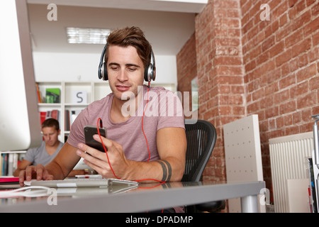 Junger Mann mit Kopfhörern mit MP3-player Stockfoto