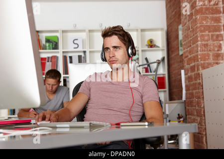 Junger Mann bei der Arbeit mit Kopfhörern Stockfoto