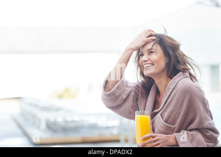 Frau am Hotel-Pool mit einem Glas Orangensaft Stockfoto