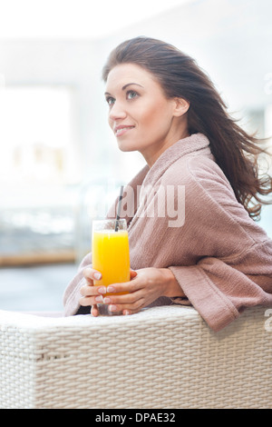 Frau am Hotel-Pool mit Orangensaft Stockfoto