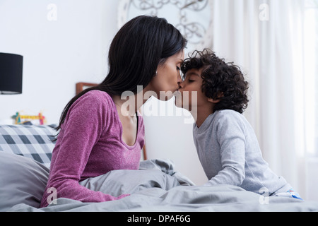 Küssende Mutter Sohn im Bett Stockfoto