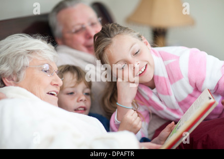 Großeltern und Enkelkinder Märchenbuch im Bett lesen Stockfoto