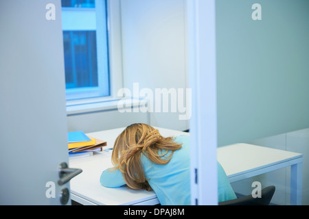 Weibliche Büroangestellte am Schreibtisch eingeschlafen Stockfoto