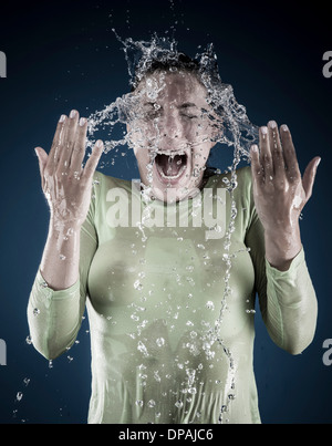 Junge Frau spritzt sich Wasser auf Gesicht Stockfoto