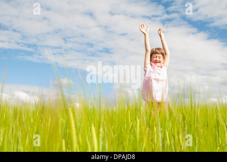 Mädchen im Feld mit erhobenen Armen Stockfoto