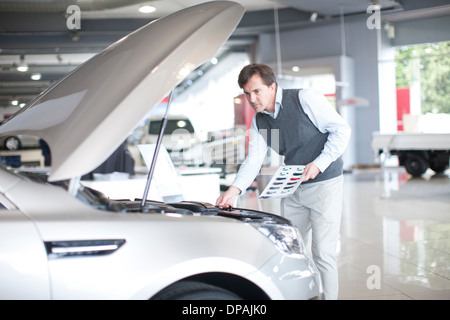 Mitte erwachsenen Mannes Überprüfung Motorhaube im showroom Stockfoto