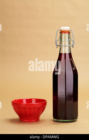 Einen leeren roten Keramikschale und eine klassische Flasche eines Hauses gemacht Rotwein auf einem Hintergrund von einem Geschenkpapier Stockfoto
