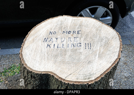 Am Straßenrand Baumstumpf mit - kein mehr Natur töten!!! -geschrieben auf ihn Autorades hinter in städtischer Umgebung, London England UK Stockfoto