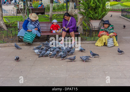 Drei Frauen und ein Baby, die füttert Tauben in der zentralen Plaza, Plaza 25 de Mayo, in Sucre, Bolivien. Stockfoto