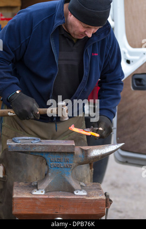 Hufschmied Hämmern rot heiß glühenden Hufeisen auf Amboss Stockfoto