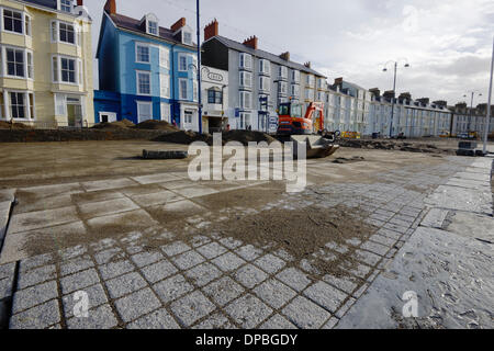 Aberystwyth, Wales, UK. 10. Januar 2014. Eine Woche nach einer schweren Sturmflut und Gale Winde zwingen beschädigt Aberystwyths Promenade, Schutt ist noch in der Gegend verstreut. Des Rates Arbeiter Klasse Flut Einlagen mit Maschinen, Sand und Pflastersteine zu trennen. Die Arbeit beginnt Abbau der Grade 2 öffentlichen Tierheim aufgeführt die Fundamente von denen am Meer untergraben wurden. Bildnachweis: Keith Burdett/Alamy Live-Nachrichten Stockfoto