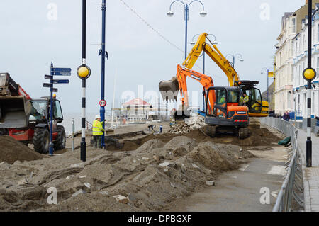 Aberystwyth, Wales, UK. 10. Januar 2014. Eine Woche nach einer schweren Sturmflut und Gale Winde zwingen beschädigt Aberystwyths Promenade, Schutt ist noch in der Gegend verstreut. Des Rates Arbeiter Klasse Flut Einlagen mit Maschinen, Sand und Pflastersteine zu trennen. Die Arbeit beginnt Abbau der Grade 2 öffentlichen Tierheim aufgeführt die Fundamente von denen am Meer untergraben wurden. Bildnachweis: Keith Burdett/Alamy Live-Nachrichten Stockfoto
