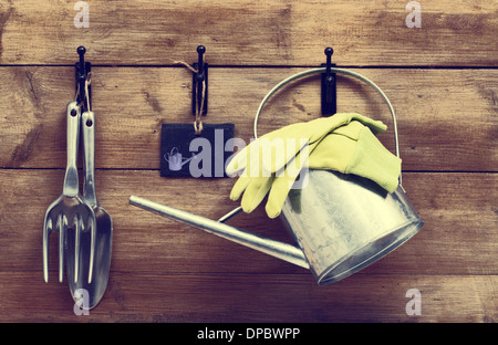 Garten Werkzeuge hängen mit Gießkanne an Schuppen Tür mit Vintage-Look Stockfoto