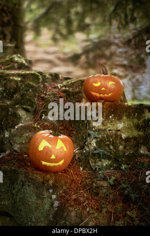 Zwei Jack O Lanterns sitzen auf einer alten Mauer mit Struktureffekt für Atmosphäre hinzugefügt Stockfoto