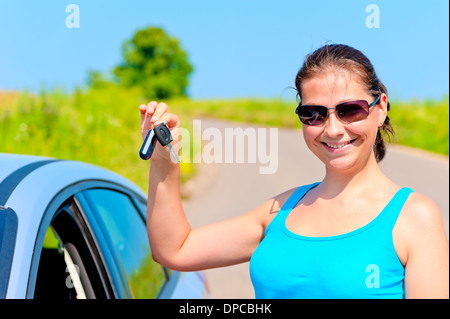 junge Frau zeigt stolz die Schlüssel zu ihrem neuen Auto Stockfoto