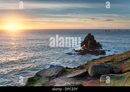 Felsen bei Lands End in Cornwall mit dem Langschiffe Leuchtturm in der Ferne Stockfoto