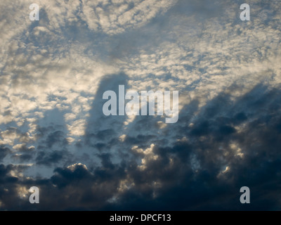 Dunkle Wolken Schatten Finger geformt auf Sonne beleuchtet flauschige Wolken, Muster in den Himmel Stockfoto