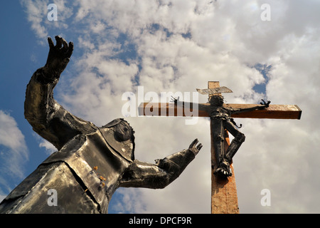 Moderne Stahl Statue von Christus mit Maria zu seinen Füßen gegen blauen Himmel Stockfoto