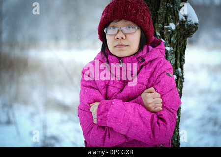 Jung und launisch Asiatin mit einer rosa Jacke im Winter an einen Baum gelehnt Stockfoto