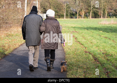 Älteres paar walking Hund in Landschaft Stockfoto