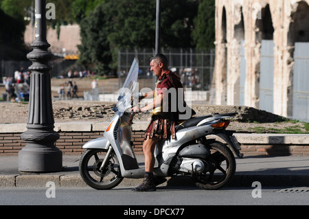 Eine römische Soldaten sitzen auf einem Moped vor dem Kolosseum in Rom, Italien. Das Kolosseum befindet sich im Aufbau. Stockfoto