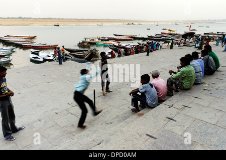 Junge Männer spielen Cricket auf den Ghats neben den Ganges in Varanasi Stockfoto