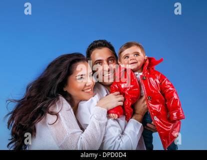 Porträt des jungen Familienglück auf blauen Himmelshintergrund, kleines Mädchen mit Mutter und Vater verbringt Zeit zusammen im freien Stockfoto