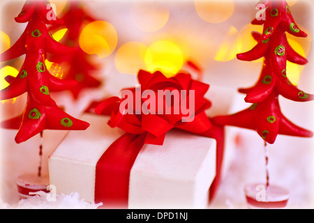 Niedliche kleine Geschenkbox verpackt in weißem Papier mit Schleife mit kleinen roten Plastilin Tanne, stilvolle Weihnachten Stillleben Stockfoto