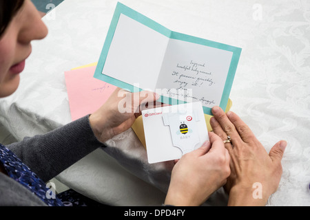 Eine werdende Mutter schaut sich eine Dusche Geschenkkarte mit ihrer Mutter. Nahaufnahme von Händen und Karte. USA. Stockfoto