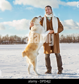 Mann und zentralasiatischen shepherd spielen mit seinem Hund im freien Stockfoto