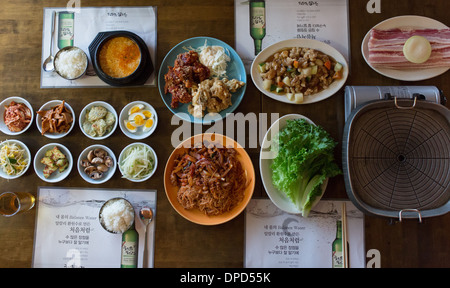 Koreanisches Restaurant Essen - gegrillter Schweinebauch, Brathähnchen, Tiefe gebratenes Schweinefleisch, Schnecke Salat, Tofu Suppe und Banchan (Beilagen) Stockfoto