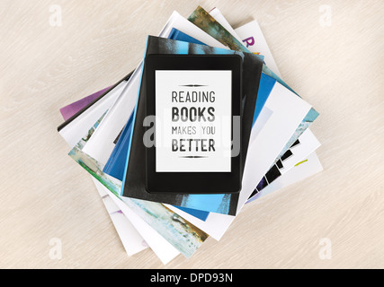 Bücher lesen macht Sie besser - Text auf einem Bildschirm des elektronischen Buches liegt oben auf einem Stapel von Büchern und Zeitschriften Stockfoto