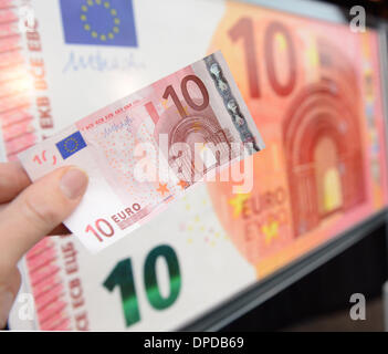 Frankfurt Main, Deutschland. 13. Januar 2014. (ABBILDUNG) Eine Hand hält eine alte zehn Euro-Banknote vor einer überdimensionalen neue Banknote in der Zentrale der Europäischen Zentralbank EZB in Frankfurt Main, Deutschland, 13. Januar 2014. Die neuen Banknoten werden am 23. September 2014 geäußert werden. Foto: Arne Dedert/Dpa/Alamy Live-Nachrichten Stockfoto