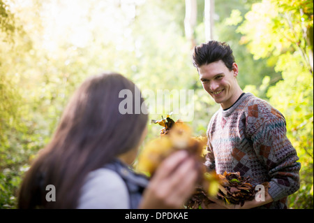 Junges Paar mit Herbstlaub im Wald spielen Stockfoto