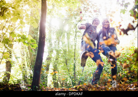 Junges Paar mit Herbstlaub im Wald spielen Stockfoto